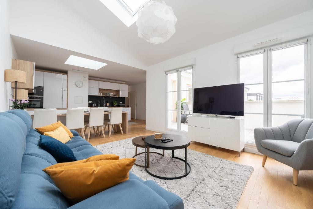 a living room with a blue couch and a tv at Appartement Fransokyo - Welkeys in Serris