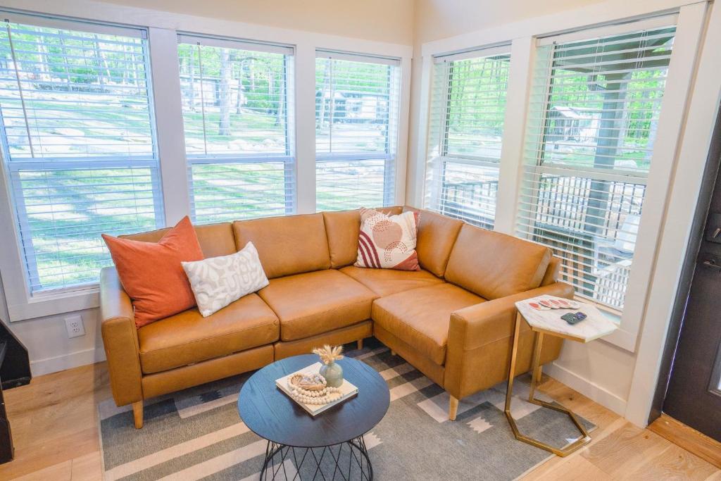 ein Wohnzimmer mit einem braunen Sofa und einigen Fenstern in der Unterkunft Farmhouse Tiny home with fishing Pond - Oak Cabin in Gatlinburg