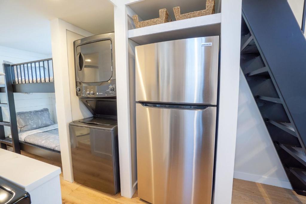a stainless steel refrigerator in a kitchen with a staircase at Farmhouse Tiny home with fishing Pond - Oak Cabin in Gatlinburg