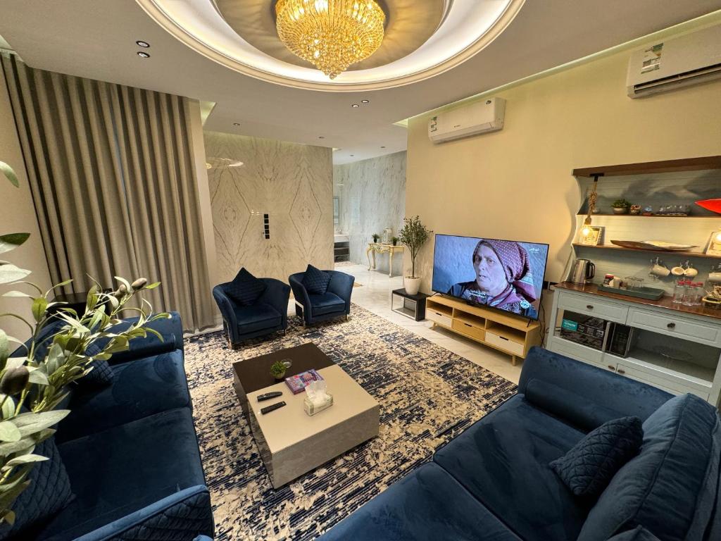 sala de estar con sofá azul y TV en شقة فاخرة غرفة وصالة بالعارض ٢ en Riad