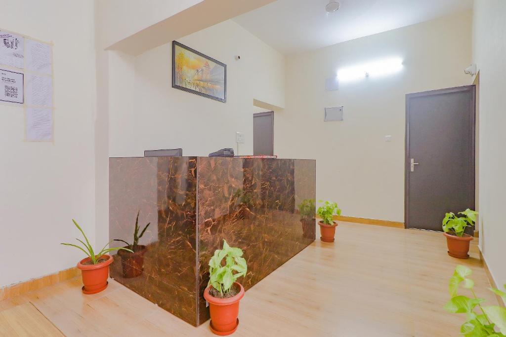 a room with potted plants on the floor and a wall at Hotel Mk Grand in Patna