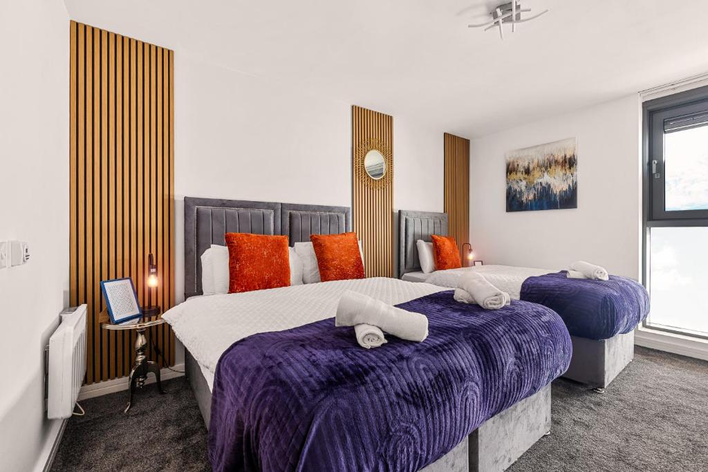 a bedroom with two beds with purple sheets and orange pillows at Bullring Lux Suite, New Street Free Netflix - Free Secure Parking- Sleeps 6 in Birmingham