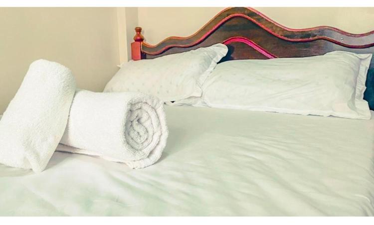 ein Bett mit weißer Bettwäsche und Kissen darauf in der Unterkunft Zuri House in Bomet