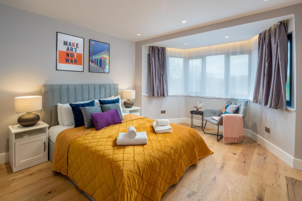 a bedroom with a large bed with a yellow blanket at Two-bedroom flat near Wembley, London in Wealdstone