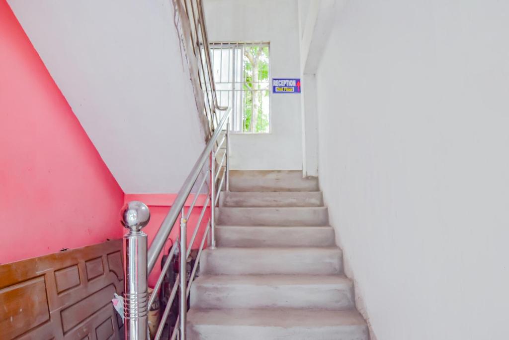 SPOT ON Nirvaan Guest House في Kāhārpāra: درج في مبنى بجدار احمر