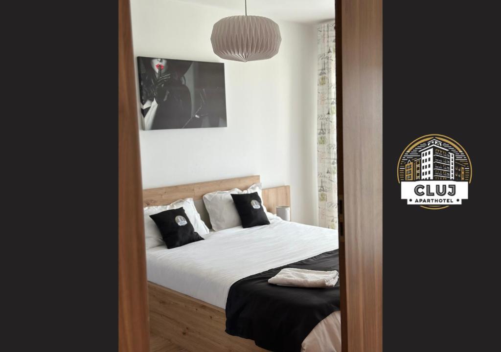 um quarto com uma cama com lençóis brancos e almofadas em Cluj Viva Aparthotel em Cluj-Napoca