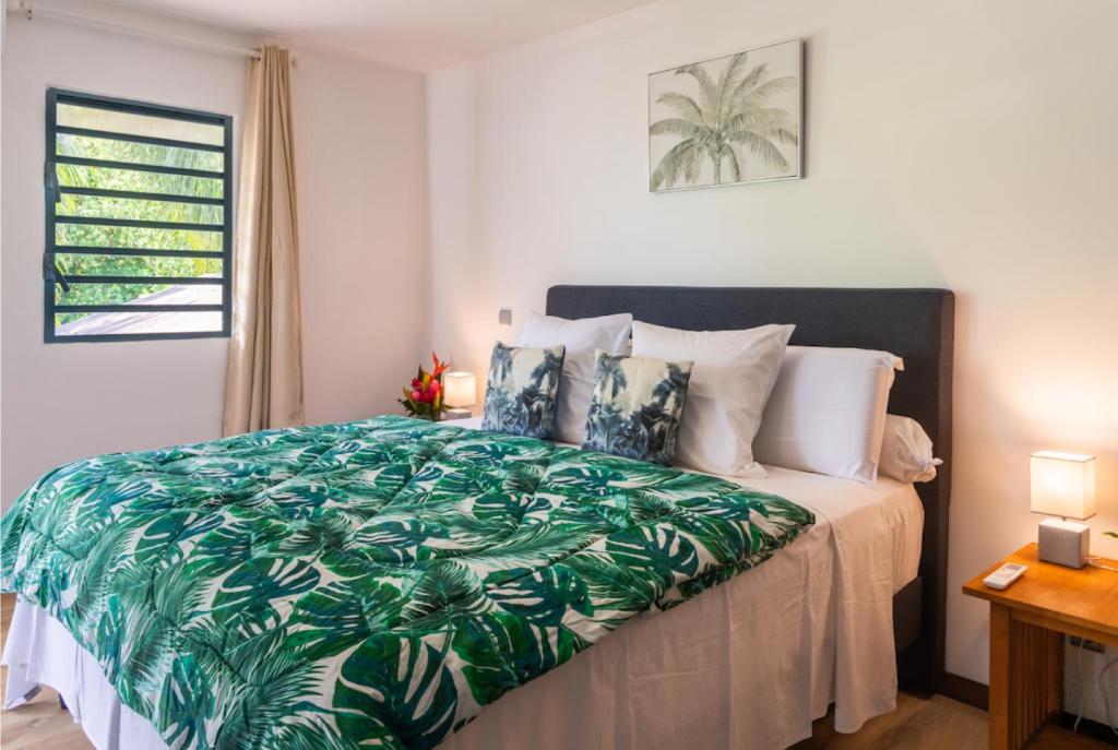 - une chambre avec un lit et une couette verte dans l'établissement Black Pearl Lodge, à Bora Bora