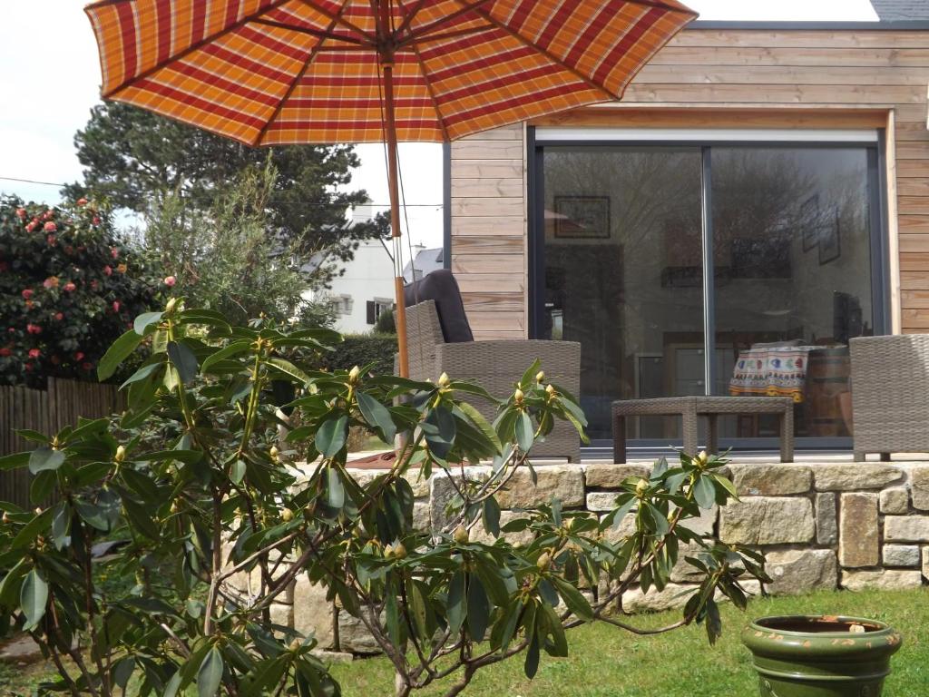 un ombrello arancione in un cortile accanto a una casa di Maison d'une chambre avec jardin clos et wifi a Guidel a Guidel