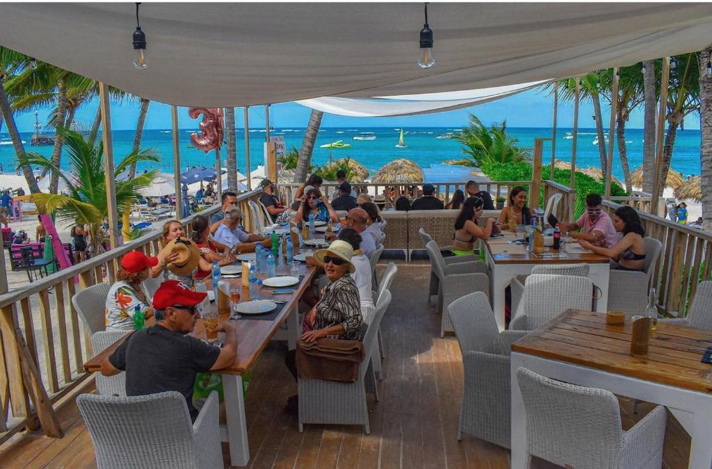 eine Gruppe von Personen, die an Tischen in einem Strandrestaurant sitzen in der Unterkunft LOS CORALES VILLAS and SUITES - BEACH CLUB, SPA, RESTAURANTS in Punta Cana