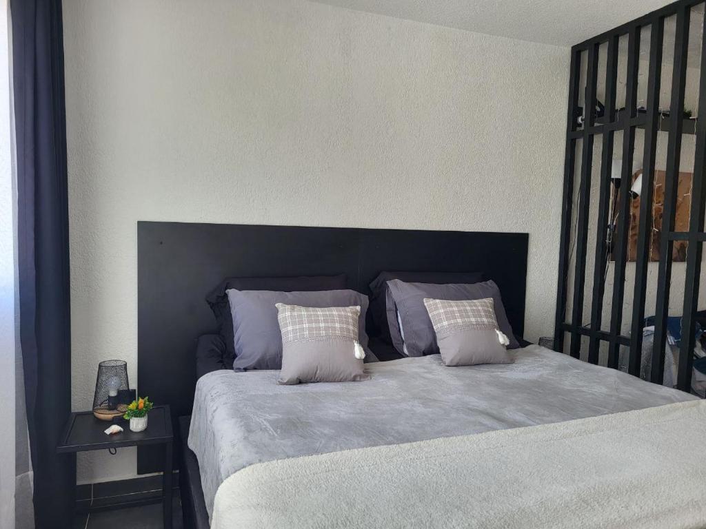 um quarto com uma cama com uma cabeceira e almofadas pretas em Apartamento en el centro de Montevideo con hermosa vista y cerca del mar em Montevidéu