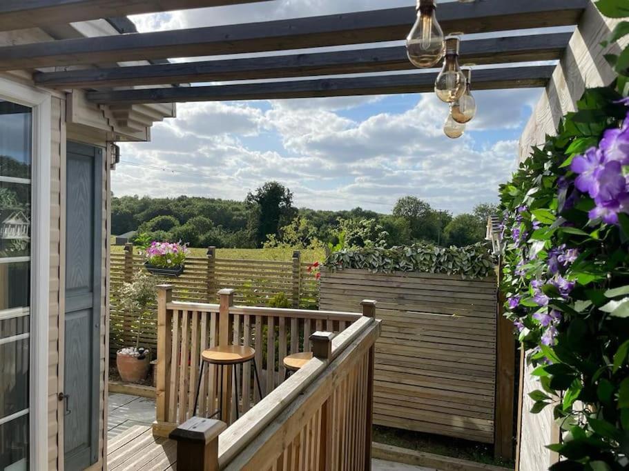 eine Holzterrasse mit einer Pergola und zwei Hockern in der Unterkunft Sunset View in Gillingham