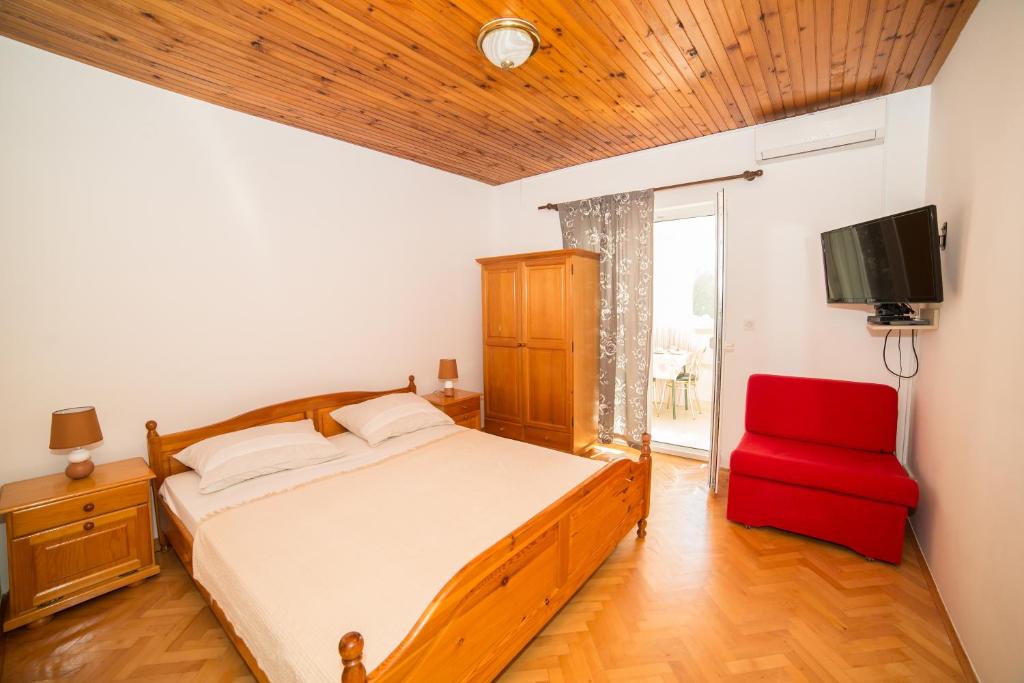 ein Schlafzimmer mit einem Bett und einem roten Stuhl in der Unterkunft Apartman Škarica in Omiš