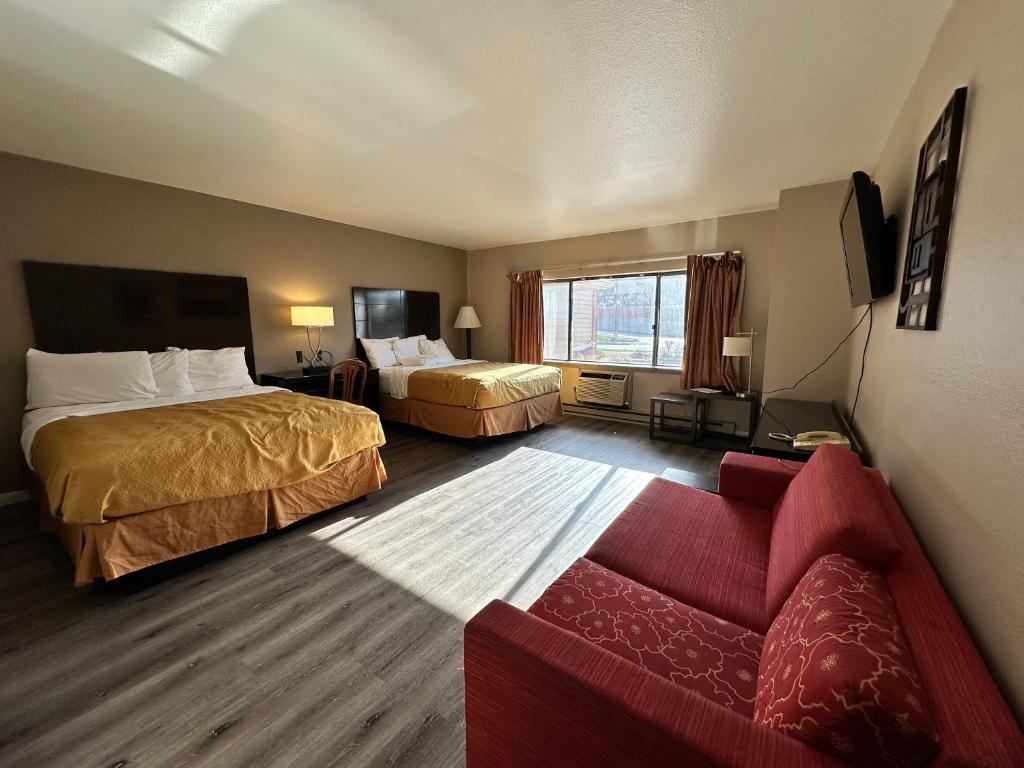 a hotel room with two beds and a couch at Rodeway Inn & Suites Madison Airport in Madison