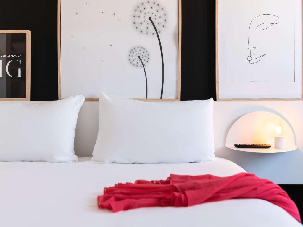a red dress laying on a bed with two pillows at ibis Styles Paris Gare de l'Est Château Landon in Paris