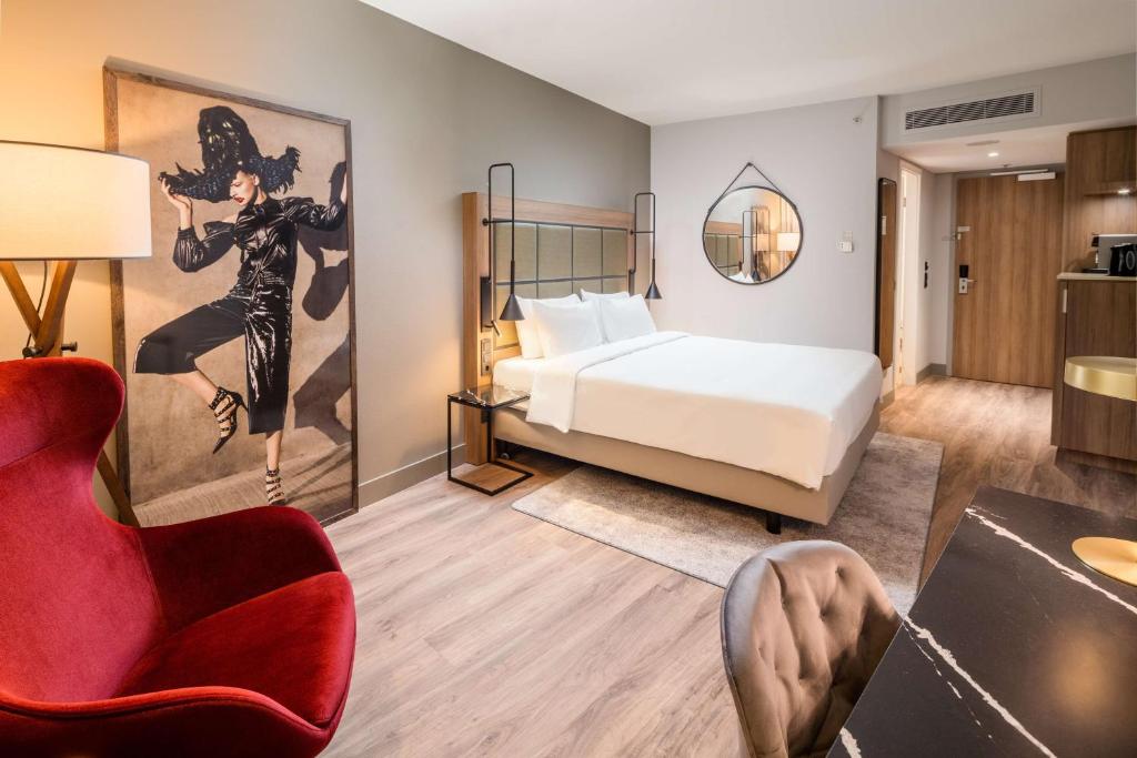 a hotel room with a bed and a red chair at Radisson Blu Hotel, Hamburg Airport in Hamburg
