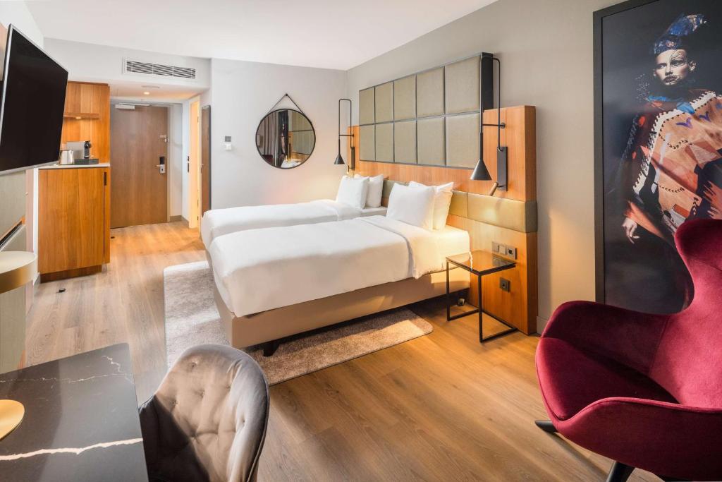 a bedroom with a large bed and a red chair at Radisson Blu Hotel, Hamburg Airport in Hamburg