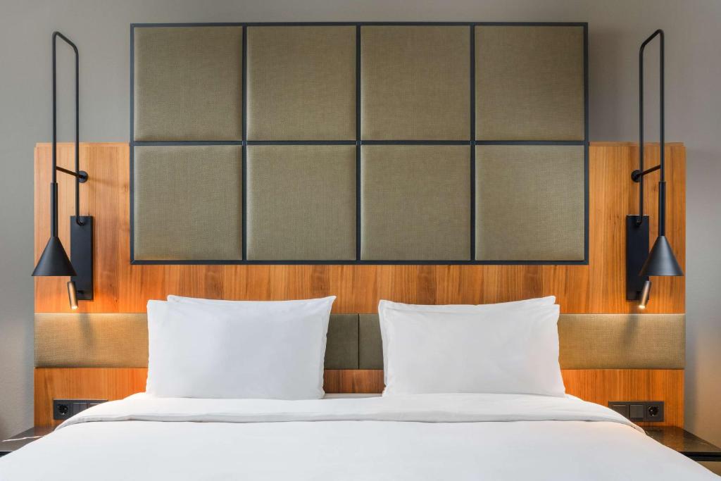 a bed with two pillows and two lights above it at Radisson Blu Hotel, Hamburg Airport in Hamburg