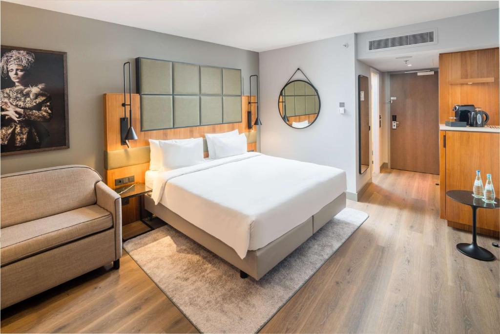 a bedroom with a large white bed and a couch at Radisson Blu Hotel, Hamburg Airport in Hamburg
