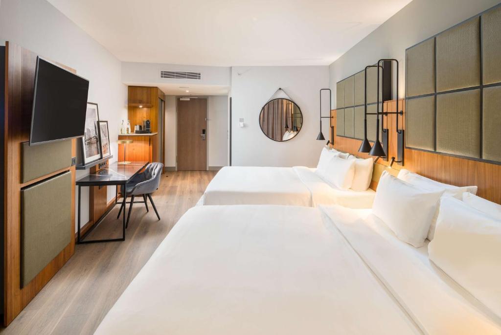 a hotel room with two beds and a desk at Radisson Blu Hotel, Hamburg Airport in Hamburg