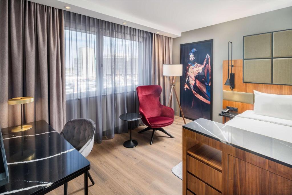 a hotel room with a bed and a red chair at Radisson Blu Hotel, Hamburg Airport in Hamburg