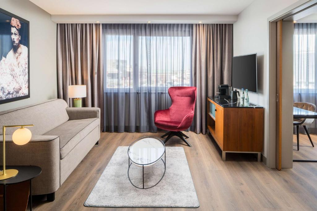 a living room with a couch and a red chair at Radisson Blu Hotel, Hamburg Airport in Hamburg