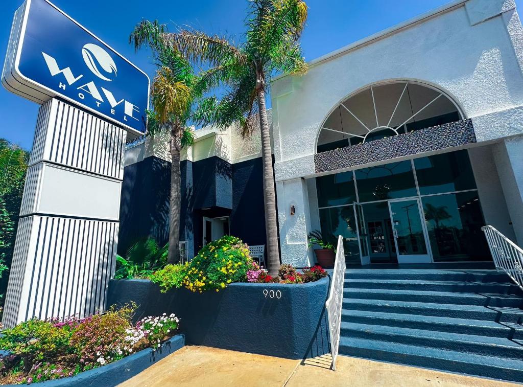 ein Schild vor einem Gebäude mit einer Palme in der Unterkunft Wave Hotel Manhattan Beach in Manhattan Beach