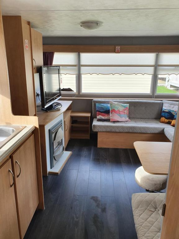 a living room with a couch and a tv in a caravan at Lyons robin Hood in Meliden