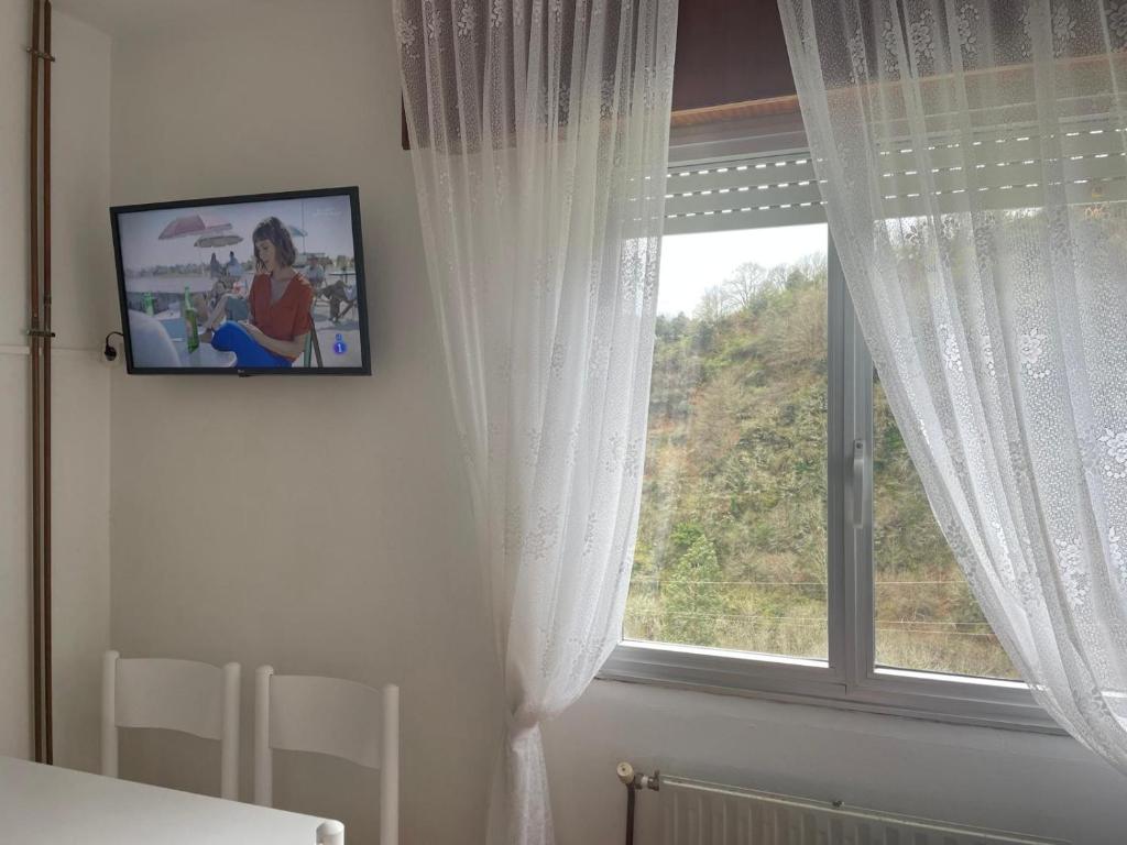 uma televisão pendurada numa parede ao lado de uma janela em Casa da Fontiña em Seoane