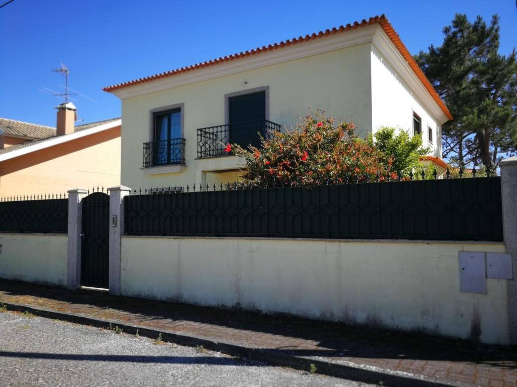 a white house with a black fence in front of it at Maria Vagueira BeachHouse in Vagos