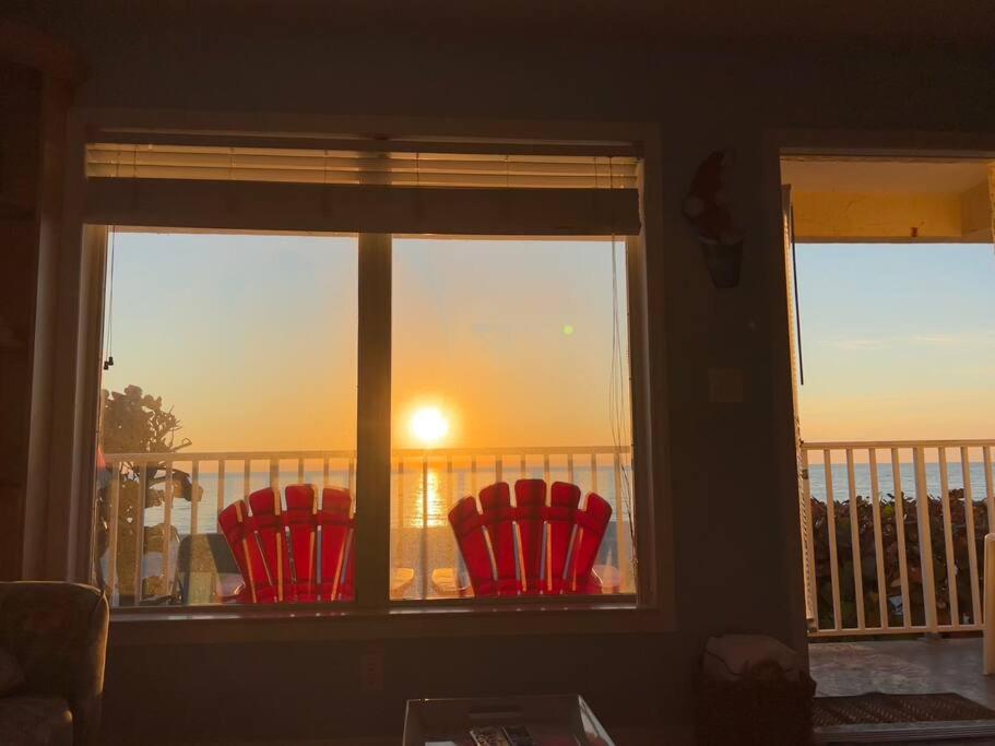 twee rode stoelen voor een raam met uitzicht op de zonsondergang bij Beachfront condo in paradise in Bradenton Beach