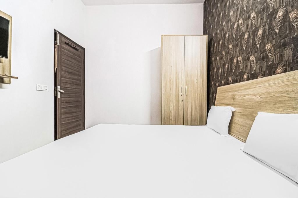 biała sypialnia z łóżkiem i drewnianymi drzwiami w obiekcie OYO Prime Property w mieście Ludhiana