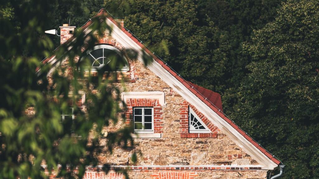un vieux bâtiment en briques avec une fenêtre et des arbres dans l'établissement DOM PIWOWARA, à Leśna