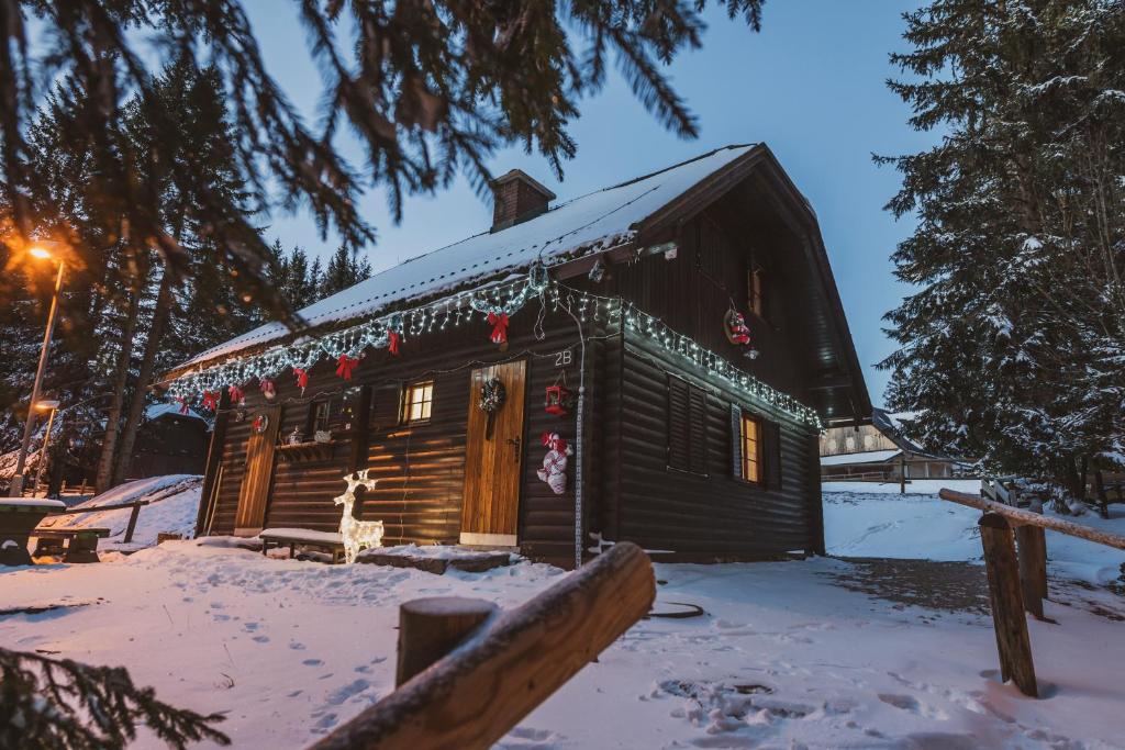 uma cabana de madeira na neve com decorações de Natal em Apartment Zarja - Trije Kralji em Zgornja Ložnica