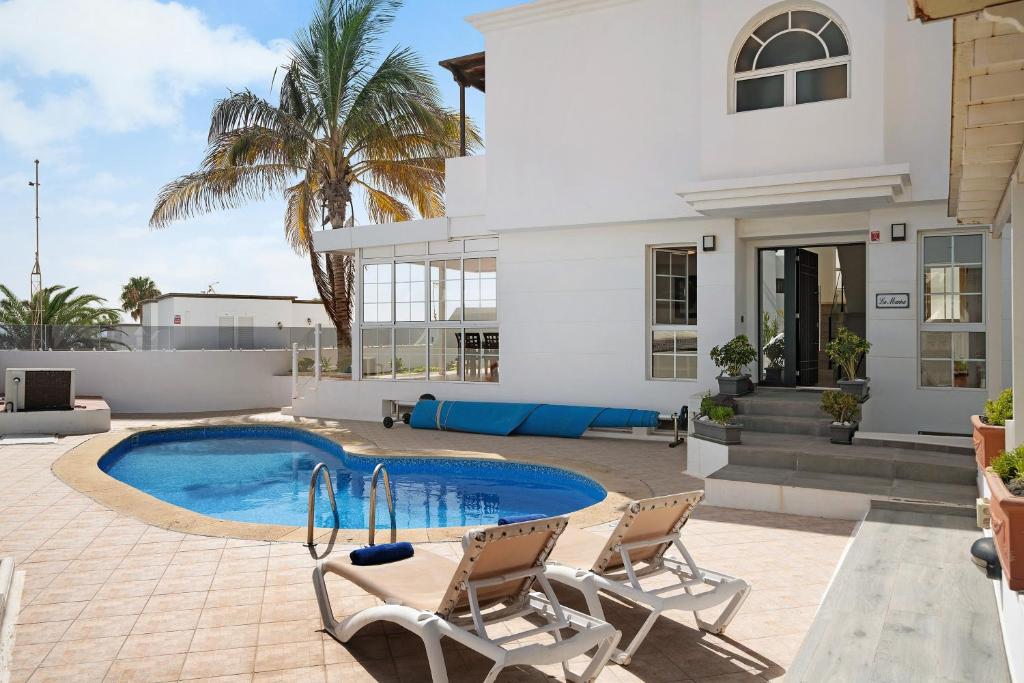 a house with a swimming pool and two chairs at La Marina in Puerto del Carmen