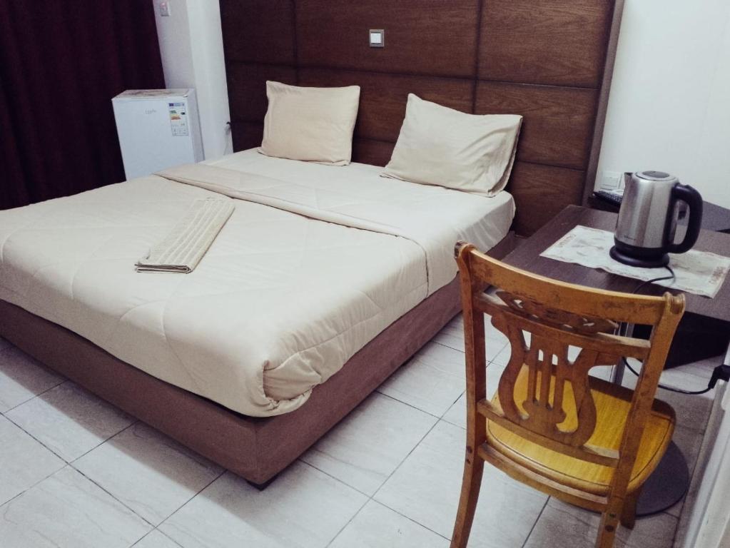 Bett mit einem Kopfteil aus Holz und einem Stuhl in einem Zimmer in der Unterkunft Amir Palace Hotel in Aqaba