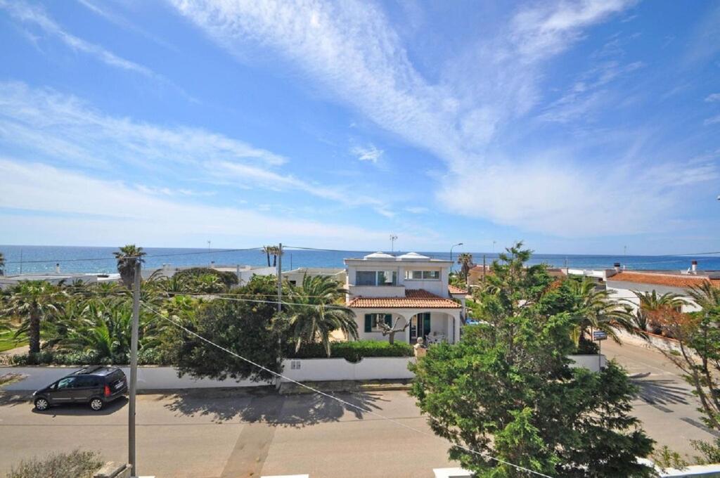 a house with a car parked in front of the ocean at Villa Sunset in Torre Suda