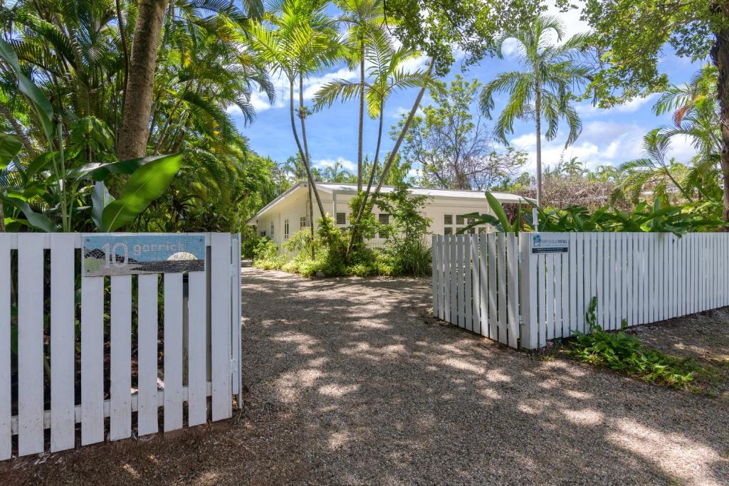una cerca blanca frente a una casa con palmeras en Coastal Chill, en Port Douglas