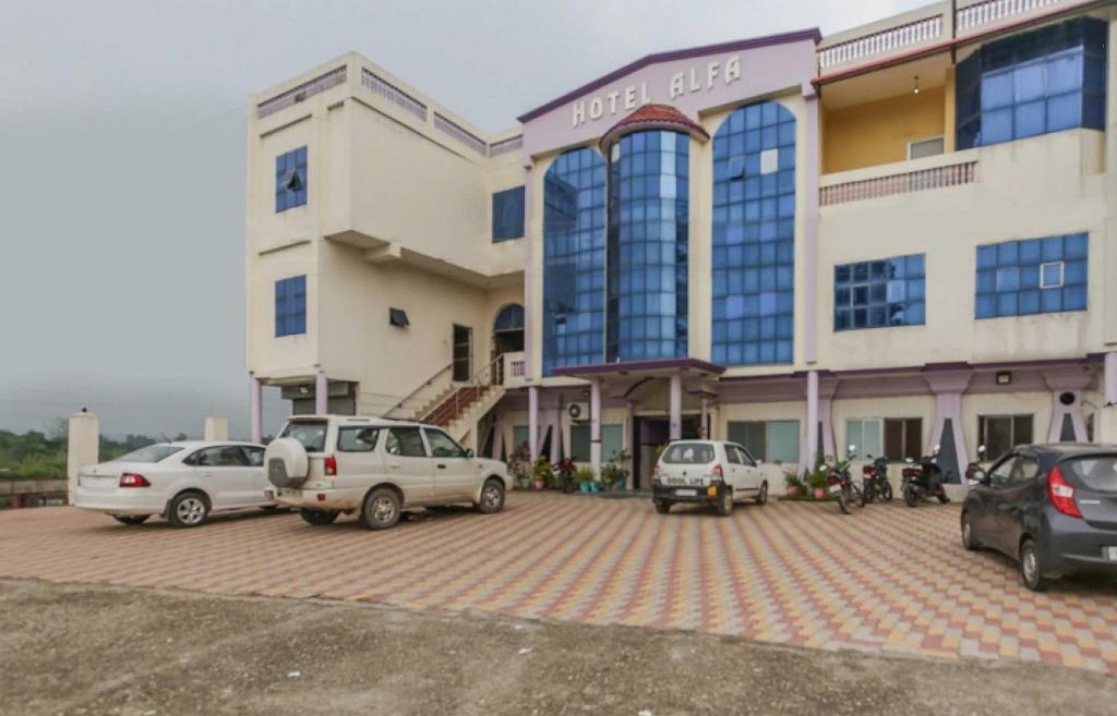 un edificio con coches estacionados en un estacionamiento en OYO Hotel Alfa, en Amb