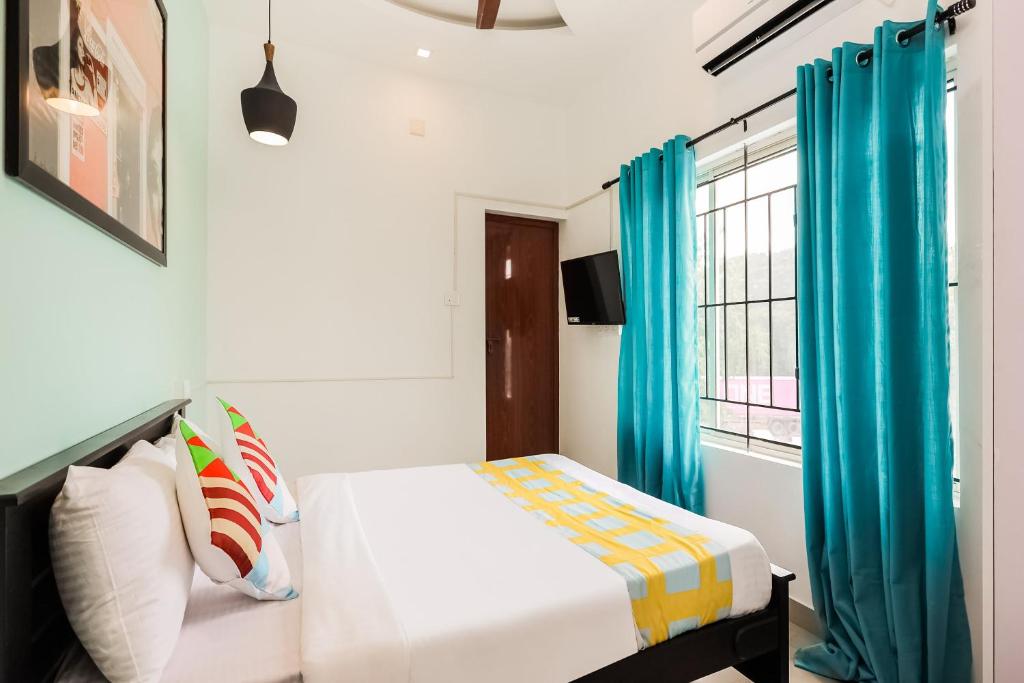 Schlafzimmer mit einem Bett mit blauen Vorhängen und einem Fenster in der Unterkunft OYO Home KC Arcade in Kochi