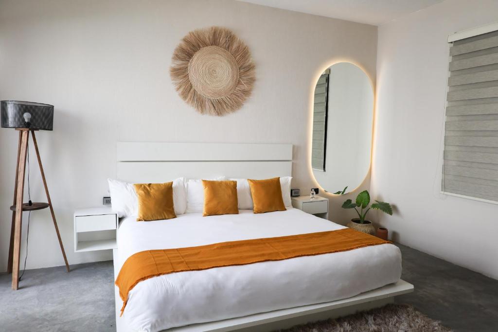 una camera da letto con un grande letto bianco con cuscini arancioni di Aura Hotel boutique a Guadalajara