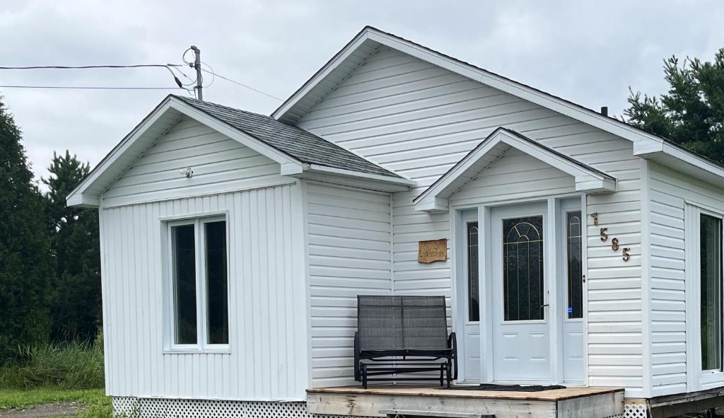 une maison blanche avec une chaise en face dans l'établissement Le Gaston, chalet en campagne, 