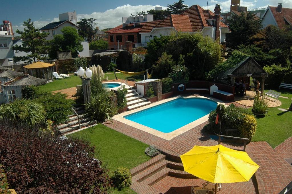 una zona de patio con piscina, silla de césped y muebles de patio en la Hostería Querandi de Villa Gesell