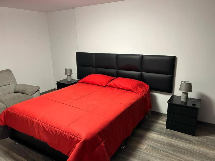 a bedroom with a red bed with a black headboard at Departamento en José Luis Bustamante y Rivero in La Pampilla
