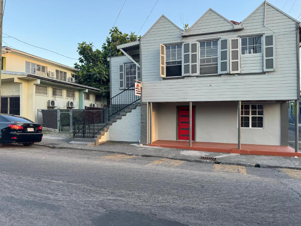 uma casa com uma porta vermelha numa rua em JJ Guest House em Branns Hamlet