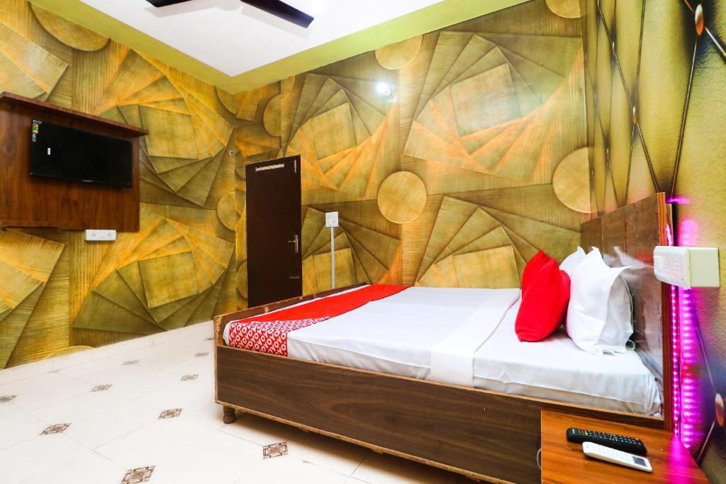 Habitación con cama y pared con mural en OYO Hotel K-sav Inn, en Phagwāra