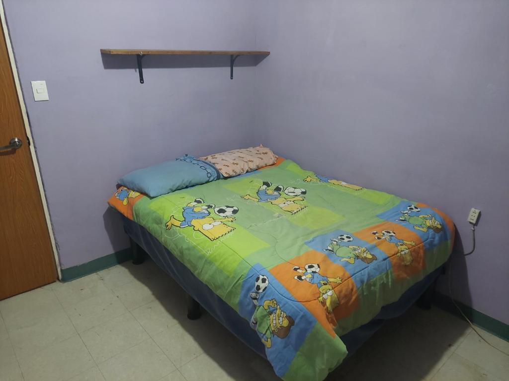 uma pequena cama com um edredão colorido num quarto em Habitación privada en Casa compartida, 4 adultos em Cidade do México