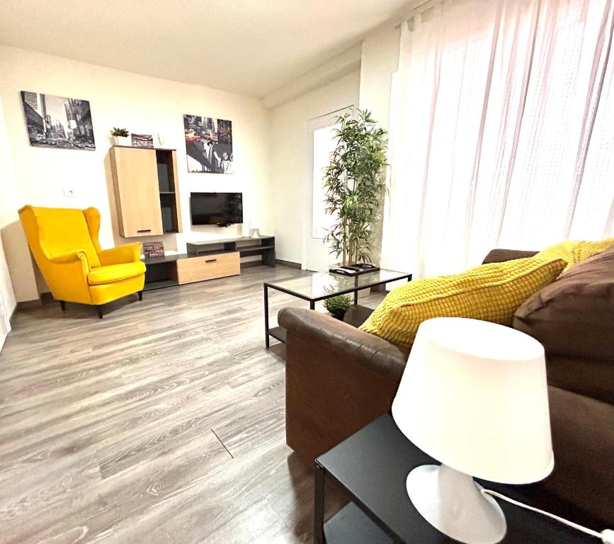 - un salon avec un canapé et un fauteuil jaune dans l'établissement Plaza Circular Más que apartamentos, à Murcie