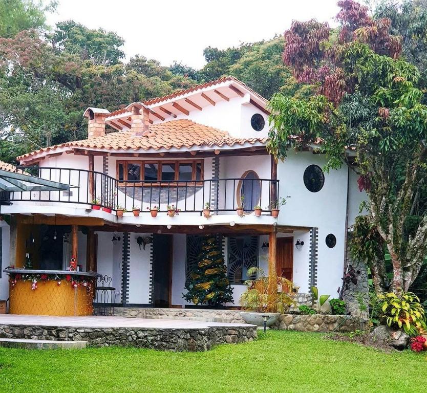 a white house with a balcony and a yard at Villa Valcore in Mérida