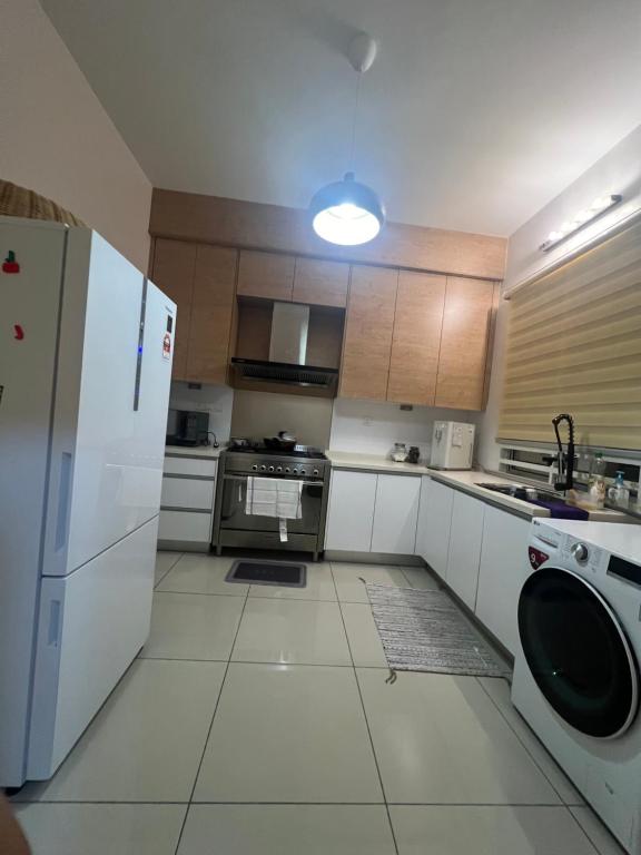 eine Küche mit einem Kühlschrank, einer Waschmaschine und einem Trockner in der Unterkunft DAHLIA LOVELY HOME in Jitra