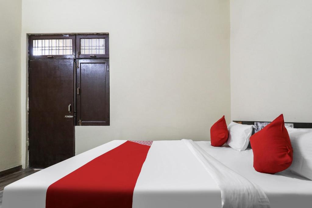 a bedroom with a bed with red pillows and a door at OYO Samrat Residency in Faridabad